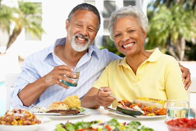 older couple eating a meal outdoors and smiling for the camera