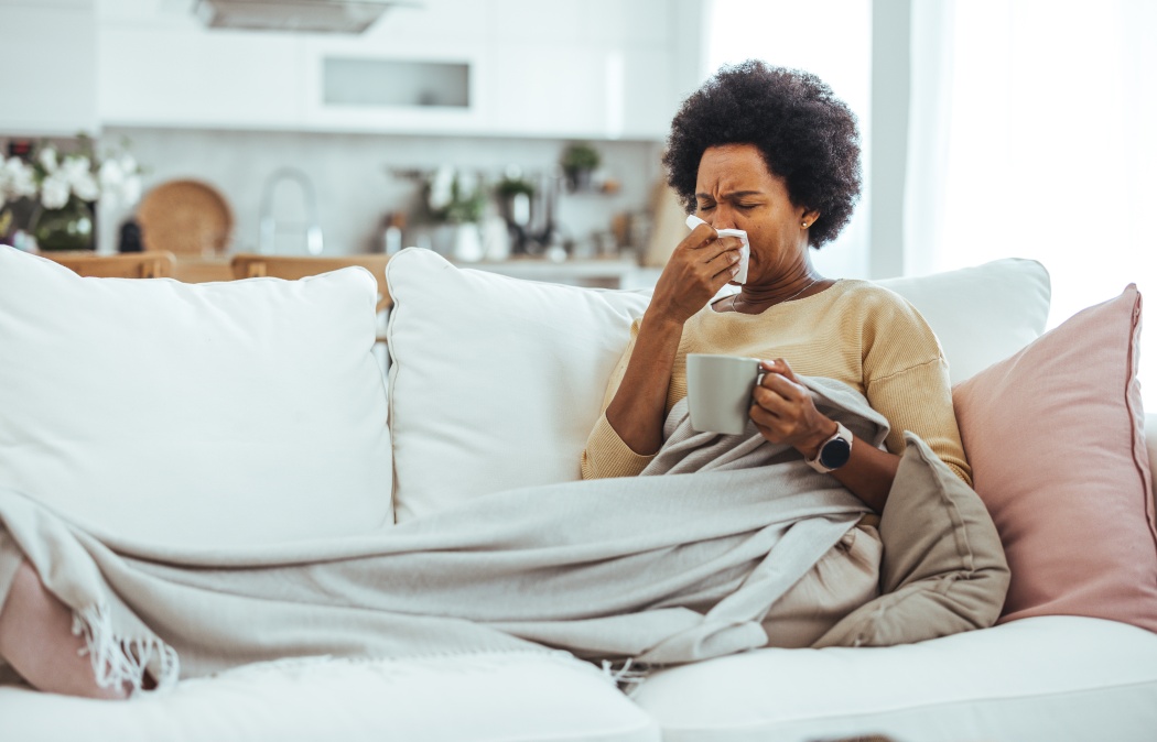 Woman with flu in bed, she use home medicine to handle sickness. Ill Woman Caught Cold, Feeling Sick And Sneezing In Paper Wipe. Closeup Of Beautiful Unhealthy Girl Covered In Blanket Wiping Nose.