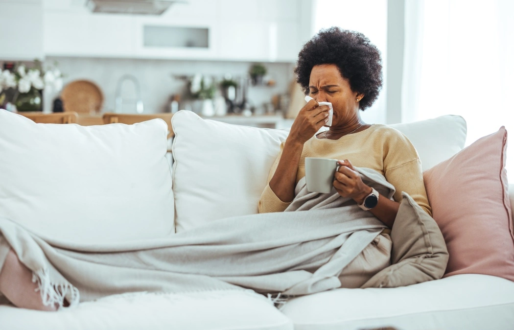 Woman with flu in bed, she use home medicine to handle sickness. Ill Woman Caught Cold, Feeling Sick And Sneezing In Paper Wipe. Closeup Of Beautiful Unhealthy Girl Covered In Blanket Wiping Nose.
